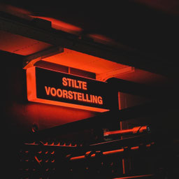 Een backstage lamp die met de tekst "stilte, voorstelling" aantoont dat er een voorstelling speelt