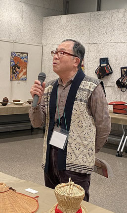展示会場で民藝品を解説する會田会長。日本民藝協会の会長でもあり、公の場面ではこぎん刺しの袖無しをよく着用されています