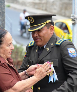 El mayor de policía Edison Molina, jefe de la Policía Comunitaria cantonal, recibe condecoración municipal de manos de la concejala Margarita Mejía. Manta, Ecuador.
