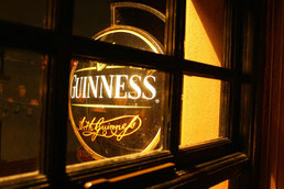 Pub mit Guinness-Schild am Abend durch ein Fenster nach außen zu sehen