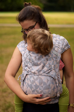 Frau mit Baby im Tragetuch auf dem Rücken