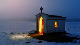 Une petite chapelle isolée la nuit dans laquelle brille une si forte lumière qu'elle éclaire l'extérieur