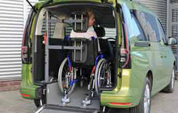 Person in wheelchair behind the steering wheel of a minivan. Powered head and backrest eFutureSafe is operated at the push of a button.