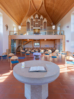 Heller, geräumiger Kirchenraum in alten Mauern mit Altar und Taufstein