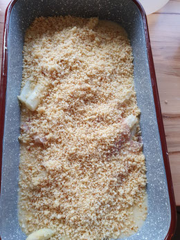 Spargel mit Käse und Brösel bestreut vor dem Backen im Ofen