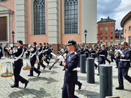 Gardesoldaten in blauen Uniformen marschieren und machen Musik.