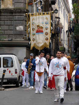 Vor Ostern ziehen Musikgruppen durch die Altstadt. Die schweren Standarten mit den Heiligen werden mit Gürteltaschen gehalten.  