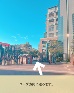 広場を通りピンクの縦ラインが入ったマンションへ進む風景。