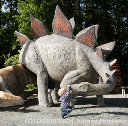 Kind spielt an Dinostatue