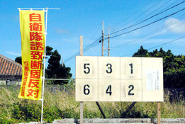 町内に設置された町長選のポスター掲示板と、近くでたなびく自衛隊誘致反対ののぼり。自衛隊配備の是非は最大の争点だが、両陣営の訴え方には相違がある(5日午後)