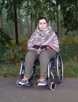 Johanna sitzt in einem Aktivrollstuhl. Im Hintergrund sieht man einen Wald. (2017)