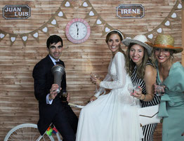 Pareja de novios e invitadas posando divertidos en photocall decorativo