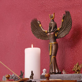 Eine Göttinnen-Statue und eine Kerze vor einem roten Hintergrund