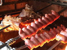 Close-up of Brazilian sausage sizzling on a charcoal grill