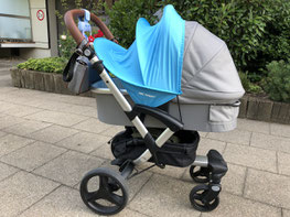 Grauer Kinderwagen steht auf der Straße bei Sonnenschein mit blauem Sonnensegel von ABC Design