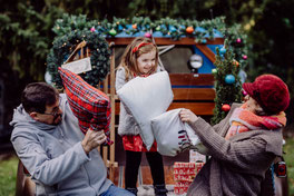 Kleines Mädchen hält einen Stern aus Holz in der Hand und steht vor bunter Weihnachtsdekoration