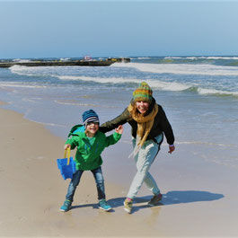 Mutter und Sohn toben am Strand