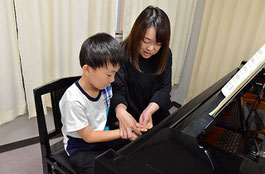 未就学児の生徒に指の使い方を教えるピアノ講師