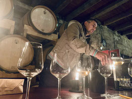 Winzer Ivo Duboković schenkt Orange Wine vor den Fässern seines Weinkellers aus.