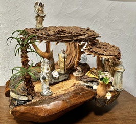 Crêche de Noël sur un pied de bois rond / toits couverts en lattes de pommes de pin / bois flottés divers / figurines 14 cm en résine