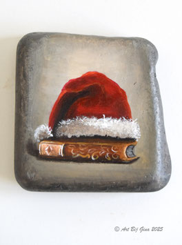 Kerstmuts op een boek geschilderd op een mooie steen