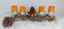 Adventsgesteck auf einem Treibholz mit orangenen Kerzen