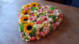 rouwhart 50 cm. opgemaakt in zachte tinten waar aan de rand zonnebloemen in zijn verwerkt