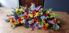 Langwerpig Rouwarrangement met blauw, paars, rood en gele tinten