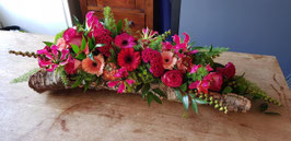 Rouwarrangement op boomschors van 80 cm. In rood,roze tinten