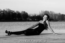 Portrait einer Frau auf einem Holzsteg an einem ruhigen See im Mühlviertel bei Sonnenuntergang