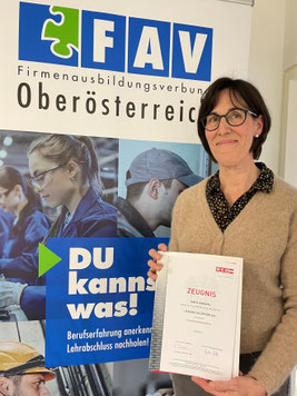 Sabine Allaburda zeigt ihr Lehrabschlusszeugnis vor dem FAV-Rollup