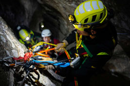 Person in persönlicher Schutzausrüstung und Stirnlampe arbeitet an einem Anschlagpunkt