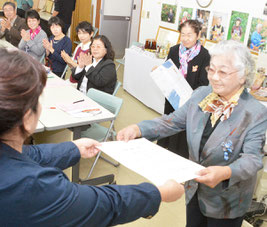 池村隊長から感謝状を受ける初代隊長の高西さん(右)。あいさつでは感謝の涙を流した=12日、沖縄県農林水産振興センター