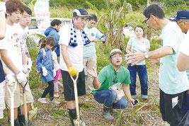 地元農家からサトウキビの捕植について説明を受ける法政大生ら=5日午後、崎枝公民館