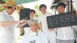 髪を切ってもらう花城新栄さんと、右から山口宏一郎さん、村瀬隆浩さん、山口奈緒美さん、坂井忍さん=20日、竹富島「ちいさな島宿cago」
