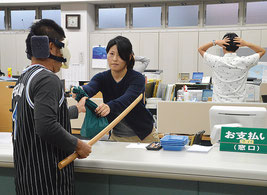 訓練で犯人役が木刀で職員を威嚇し、600万円を強奪したという設定=24日、沖縄振興開発金融公庫八重山支店