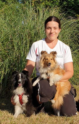 Hundetrainerin Iris Jakobi posiert kniend mit ihren beiden Shelties vor Pampasgras.