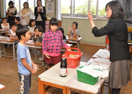 商品がつめ込まれた買い物かごを使い、児童が役割演技を行った=22日、大浜小学校