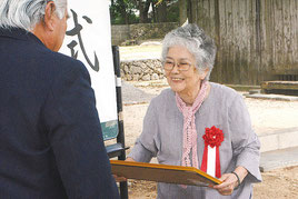 石垣字会の池城会長から感謝状を受け取る潮平俊さん=3日、宮鳥御嶽のみやとり文庫前