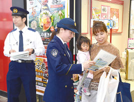 八重山署の警察官が市内のスーパーで110番通報の仕組みなどを記したチラシを配布した=8日、市内スーパー