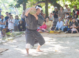 川平の豊年祭でビッチュルを肩に上げ、奉納する担ぎ手=25日午後、赤イロ目宮鳥御嶽