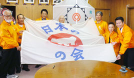 全国大会旗を持ち、県内初の全国大会をアピールする八重山凧愛好会役員=4日午後、市役所