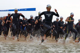 号砲とともに海に飛び込む第1ウエーブの選手=16日午前、南ぬ浜人工ビーチ