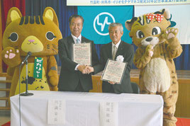 堅い握手を交わす川満町長(左)と対馬市の比田勝副市長=8日、竹富町離島振興総合センター