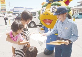 相談案内のチラシを配る當山警務係長(右)と受け取る市民=11日午前、サンエー石垣シティ