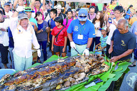 120㌔のカジキの丸焼きに歓声をあげる来場者ら=3日午後、久部良漁港