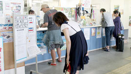 船会社に掲示された運航状況や台風情報を確認する観光客=21日午後、離島ターミナル