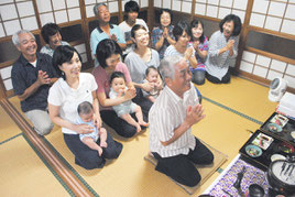 文之さんを筆頭に、仏壇に手を合わせて先祖に感謝する大盛さん一家。今年は一族に子どもが3人誕生し、笑顔が絶えない=26日夜、石垣市真栄里