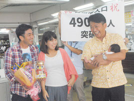 宇根底さん夫婦に花束を贈呈し、長女の沙和ちゃんを抱く中山市長=13日午前、市役所