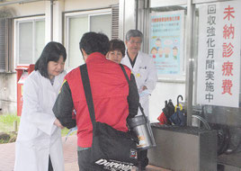 未収金対策強化月間をPRするチラシを来院者に配布する依光院長=2日午前、八重山病院